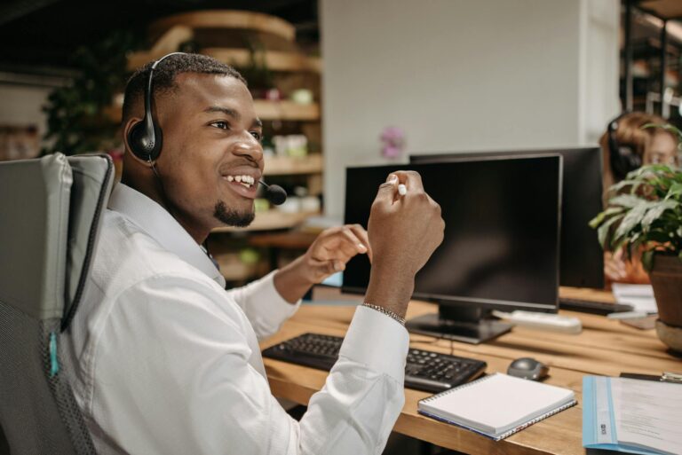 African American man smiling while working in a modern office, wearing a headset.