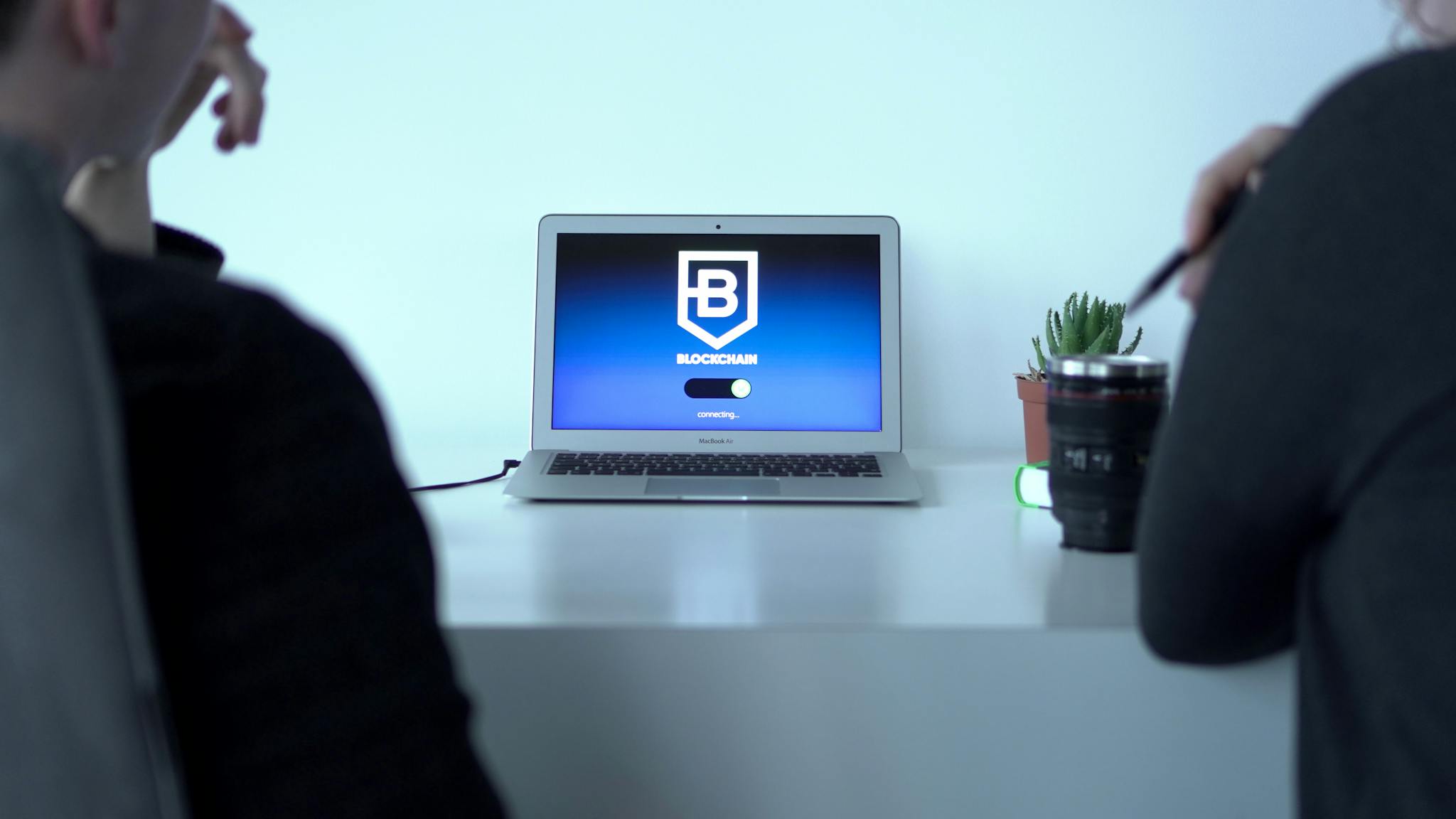 Colleagues discussing blockchain technology with a laptop in a modern office setting.